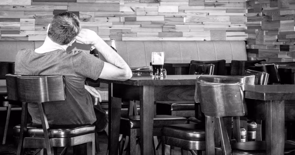 Man sitting alone at a bar reflecting on his life -- midlife crisis signs in men over 40
